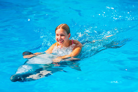 快乐的小女孩与海豚在海豚馆游泳水池女孩喜悦假期宠物潜水童年朋友海洋治疗图片