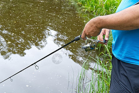 鱼手在夏季湖上旋转和卷线 贴近低音闲暇娱乐假期竞赛男性垂钓者纺纱支撑池塘图片