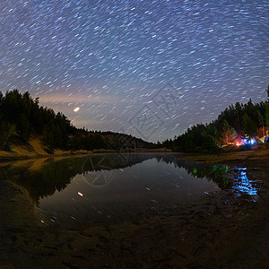 夜间有短铁轨和夏季露营的恒星下小湖图片