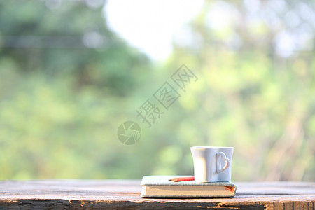白色杯子 用笔记本在有自然观的木制桌上植物木头咖啡花园园艺桌子饮料季节植物学图片