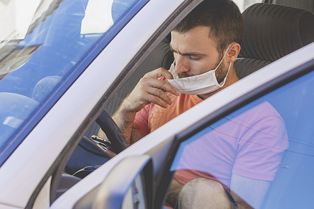 一个戴着布面罩的年轻人正在检查车内的手机司机胡须成人安全面具窗户水平中年人社会座位图片