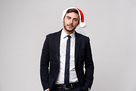 身着西装和圣诞老人帽子的英俊大帅帅哥 在工作室和牙齿微笑中站在白色背景上图片