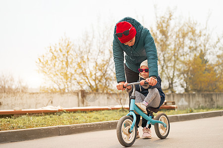 一位年轻的高加索母亲教一个女儿 在温暖的秋天骑自行车 (笑声)图片