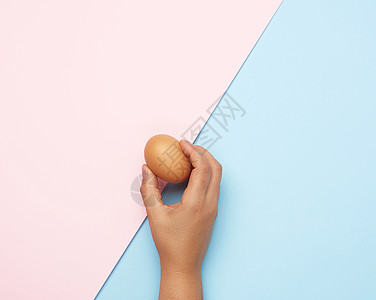 女性手握着一整只棕色鸡蛋图片