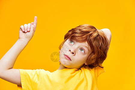 红头发男孩前视镜显示在黄色T恤上方 上面有食指近身的黄色T恤点 复制空间图片