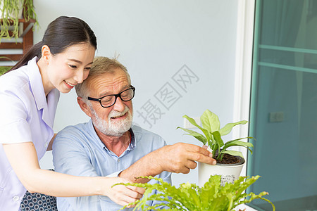 退休老人和护士正在给一家小工厂浇水 而植物男人房子魅力老年父亲闲暇园艺花朵后院图片