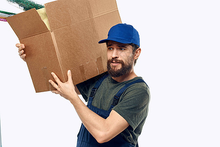 一个穿着工作制服 双手装着盒子的男士 运送运输工事服务邮件船运装载机送货工人人士包装蓝色运输图片