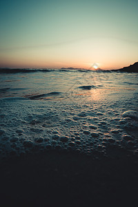 日落时沙滩潮水的泡泡 超级紧闭图片