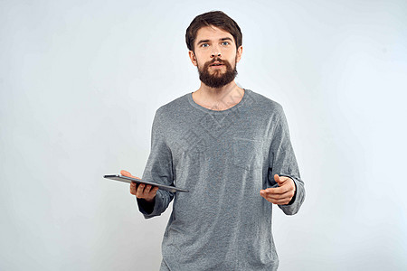 一个穿灰色毛衣的男人 一张平板在情感的手中 互联网技术 生活方式光背景相机商业衬衫商务人士成人男性工作室软垫屏幕图片
