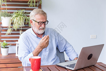 退休老人在家庭感觉上用笔记本电脑工作技术冲浪桌子互联网木头商业老年闲暇男人房间图片