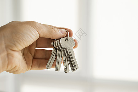 男士手拿着一组钥匙 房地产经纪人正在将公寓钥匙交给客户 专注于按键 房地产经纪人手中的一串钥匙财产金属贷款商业房子成功住宅房东建图片