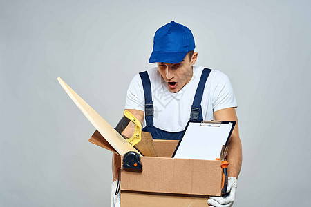 男子在工作时穿制服 手拿着一个盒子用工具装货车送货轻型背景工人装载机商业邮政人士套装船运蓝色商务成人图片