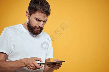 在白色T恤衫上用黄色背景的平板牌男子 商务人士触摸屏幕触摸板的新科技工作室互联网成人办公室软垫衬衫药片人士商业电脑背景图片