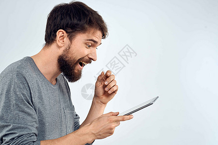 一个手手里拿着平板电脑的男人 互联网科技通讯灰色夹克光背景的白衣相机男性商务工作室白色人士软垫商业快乐衬衫图片
