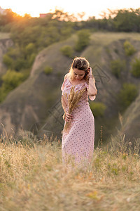 穿着白外衣的美丽年轻女孩 在日落时走在田地里 带了根花束女性荒野文化小穗村庄微笑乐趣收成植物小麦图片