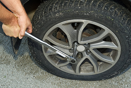 机械手用手拆开一辆在千斤上举起的汽车的平板轮胎 把车架卸下一个扁轮胎维修情况司机爆胎工作事故帮助损害保险服务图片