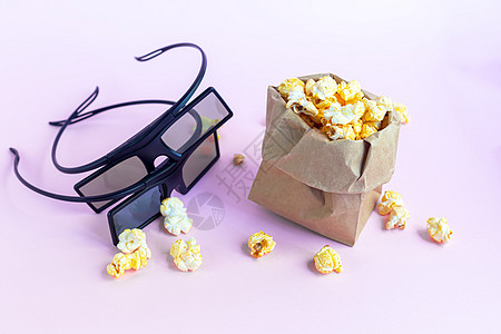 粉色表面有爆米花的纸杯 附近有3D眼镜和电视遥控器 在隔离区看电影盒子垃圾笔记本电影饮料家庭咖啡食物电脑生态图片