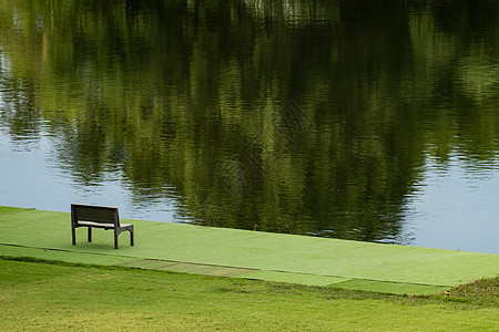 靠近河流和绿景的木椅子天空阳光长椅花园森林树木旅行公园板凳环境图片
