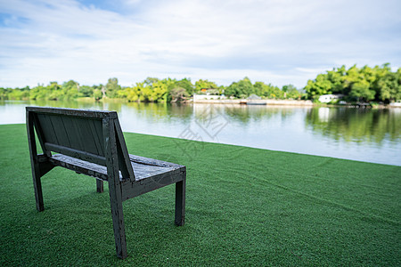 靠近河流和绿景的木椅子美丽草地环境板凳长椅阳光花园假期树木公园图片