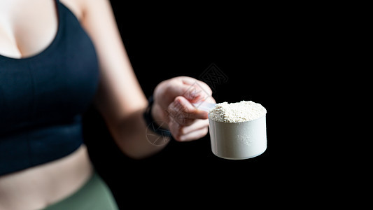 近身手握着一勺鱼蛋白质的女子获得者训练活力肌肉粉末产品食物塑料勺子健身房图片