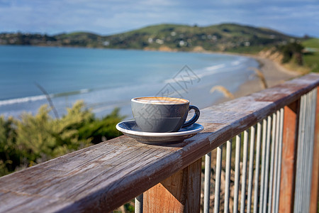 一杯咖啡杯在Verandah 铁路上对抗海景图片