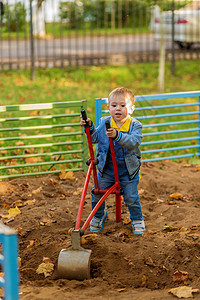 小男孩玩玩具挖掘机 在秋天公园的操场上玩耍娱乐快乐服装公园微笑男生小学婴儿童年阳光图片
