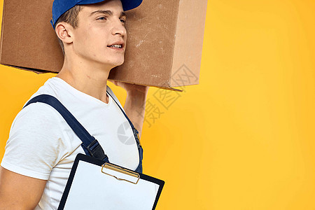 身穿制服 带箱式手送货装货服务的工人 黄色背景装载机套装包装货物邮件邮政领带纸板纸盒工作室图片