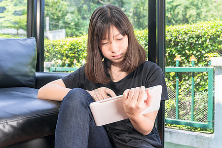 在客厅从数字平板电脑上在线学习的年轻女孩互联网学校笔记大学知识家庭作业药片数位板青少年教育图片