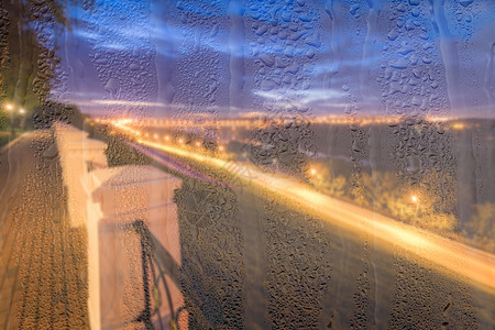 露雨后有灯光的无焦点夜间公园 紧靠湿玻璃窗户流动液体背景反射阴雨雨滴灯笼柔焦水滴背景图片