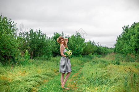 一位美丽的金发年轻女孩收集了一束野花花 在温暖的夏日散步成人自由喜悦女性裙子乐趣草地头发微笑享受图片