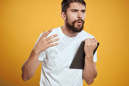 在白色T恤衫上用黄色背景的平板牌男子 商务人士触摸屏幕触摸板的新科技人士触摸屏工人成人工作室软垫商业展示成功办公室图片
