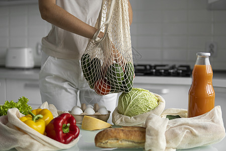 女性手持可再利用的生态纺织装有蔬菜和水果的杂货袋 零废物和无塑料概念 女孩用蔬菜包着网状棉购物者产品网袋杂货店厨房杂货棉布购物市图片