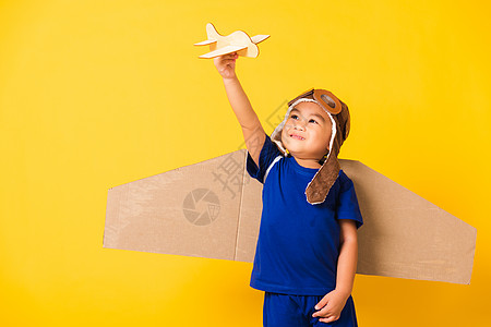 小男孩笑笑 戴着飞行员帽子玩耍 带着玩具卡的护目镜孩子喷射自由幸福冒险纸板飞机乐趣运动男生图片