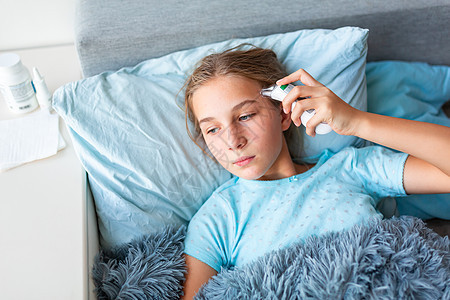 患有高发烧和头痛病症的十几岁少女躺在床上检查体温毯子说谎药品卫生温度女性流感疾病童年孩子图片