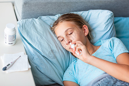 高发高烧和头痛的生病少女在床上躺着 向鼻子喷洒药剂药品温度计流感女孩童年枕头病人孩子毯子发烧图片
