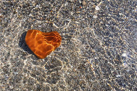 沙滩上的橙色心形石头环境卵石海洋碎石鹅卵石假期材料宏观海岸岩石图片