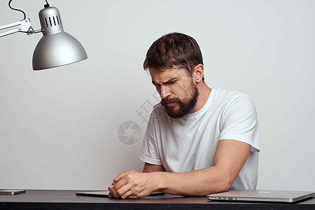 一个桌上拿着平板电脑的男人用手在浅色背景和一盏铁灯上做手势人士创造力金融职业桌子情感沉思设计师工作商务图片
