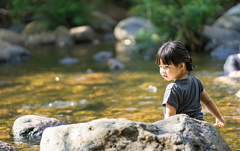 小亚洲女孩在瀑布小溪里玩 水喷着水喜悦乐趣石头白色幸福旅行公园假期闲暇孩子图片