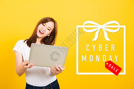 女青少年微笑站着穿T恤衫 拿着手提电脑成功销售笔记本女士工作室金融卡片购物信用商业图片