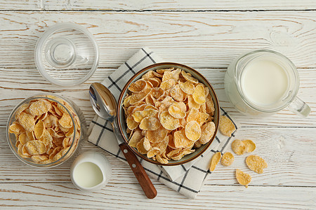 与木制白木桌面和牛奶一起早餐的概念桌子玉米片食物饮食纤维勺子玻璃营养餐巾粮食图片