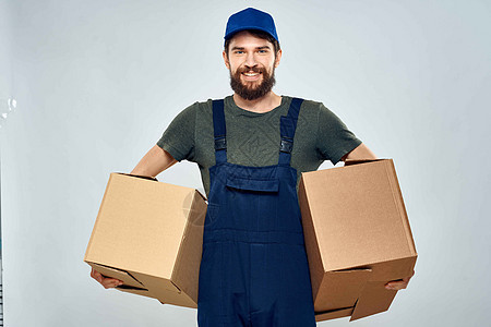 男子穿着制服 手持装箱的送货员穿工作服 随身携带衣物工作室纸盒盒子工作纸板送货人士工人商业邮政图片