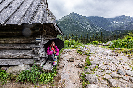 妇女躲在塔特拉山区避难所屋顶下躲避雨雨图片