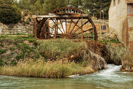 旧木制水轮和卡布里尔河经过西班牙阿尔贝塞特村水车荒野植被反思叶子碎石灌溉河岸植物农业图片