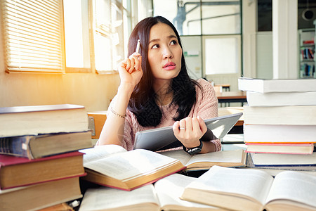 在图书馆使用平板板的年轻妇女药片笔记本大学女士知识电脑教育书架成人女孩图片