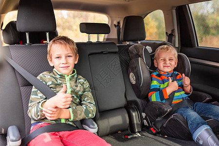 两个小男孩坐在汽车座椅上 一个助推座被扣在车上儿子兄弟椅子警告男生婴儿家庭车辆幼儿园预防图片