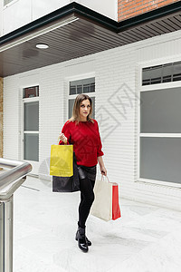 女人在商场里走过 带着多彩的购物袋红色购物消费者闲暇黑色店铺顾客零售销售购物者图片