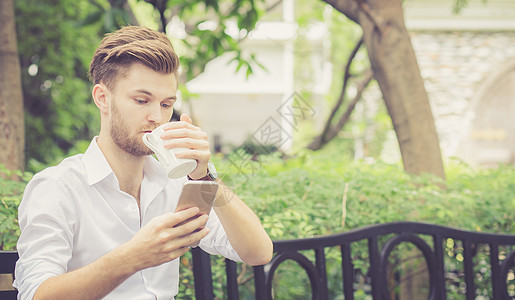商业英俊的年轻帅哥 喝咖啡 用手机Pho咖啡店咖啡公园成人商务工作办公室工具人士互联网图片