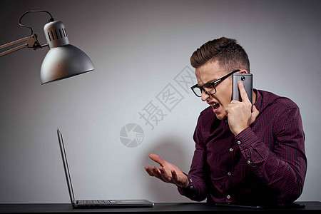 手戴眼镜和衬衫的商务人士坐在一张有开放式笔记本电脑的桌子上博主自由职业者互联网阁楼男性办公室屏幕展示工作室商业图片