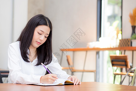 美丽的商业女青年 在小报上写笔记本店铺职场学习女性手机金融学生笔记键盘数据图片