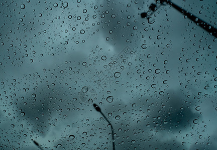 透明玻璃上的雨滴 对抗模糊的黑暗风暴天空图片